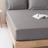 A neatly made bed with Linenly Stone Grey Bamboo Fitted Sheets, suggesting a cozy reading spot.
