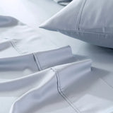 Crisp and clean grey bedding with a focus on a neatly folded corner, showcasing the soft texture and meticulous stitching. The set is enhanced by Linenly's organic Bamboo Pillowcase Set in Pale Blue, featuring a smooth satin weave for ultimate comfort.