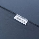 A close-up of a seam on the Luxe Cotton Sateen Fitted Sheet - Midnight by Linenly shows a white "SHORT SIDE" label, marking the shorter edge. Made from premium long-staple cotton, the dark blue fabric adds luxurious comfort.