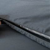 A close-up of a hand unzipping the Luxe Cotton Sateen Quilt Cover - Charcoal by Linenly, revealing a white padded layer inside.