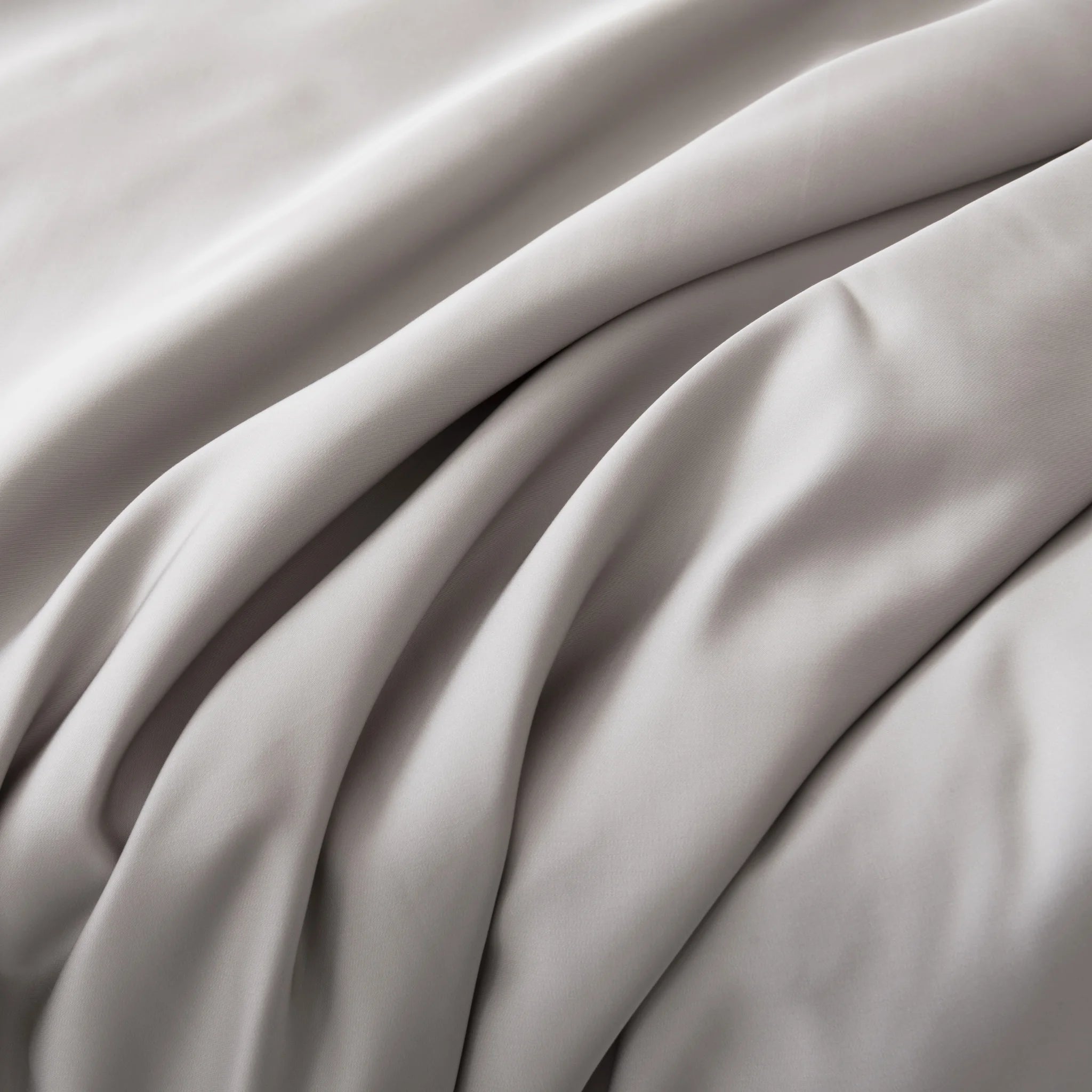 Close-up of the Bamboo Pillowcase Set - Silver by Linenly, showcasing smooth, light gray organic bamboo fabric with soft folds and gentle shadows that highlight its luxurious texture and elegant movement.